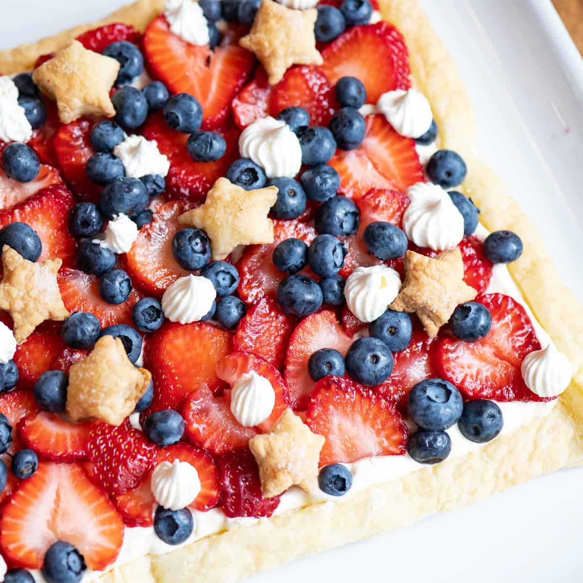 Overhead view of a patriotic Berries and Stars dessert with star-shaped puff pastry and fresh strawberries and blueberries.