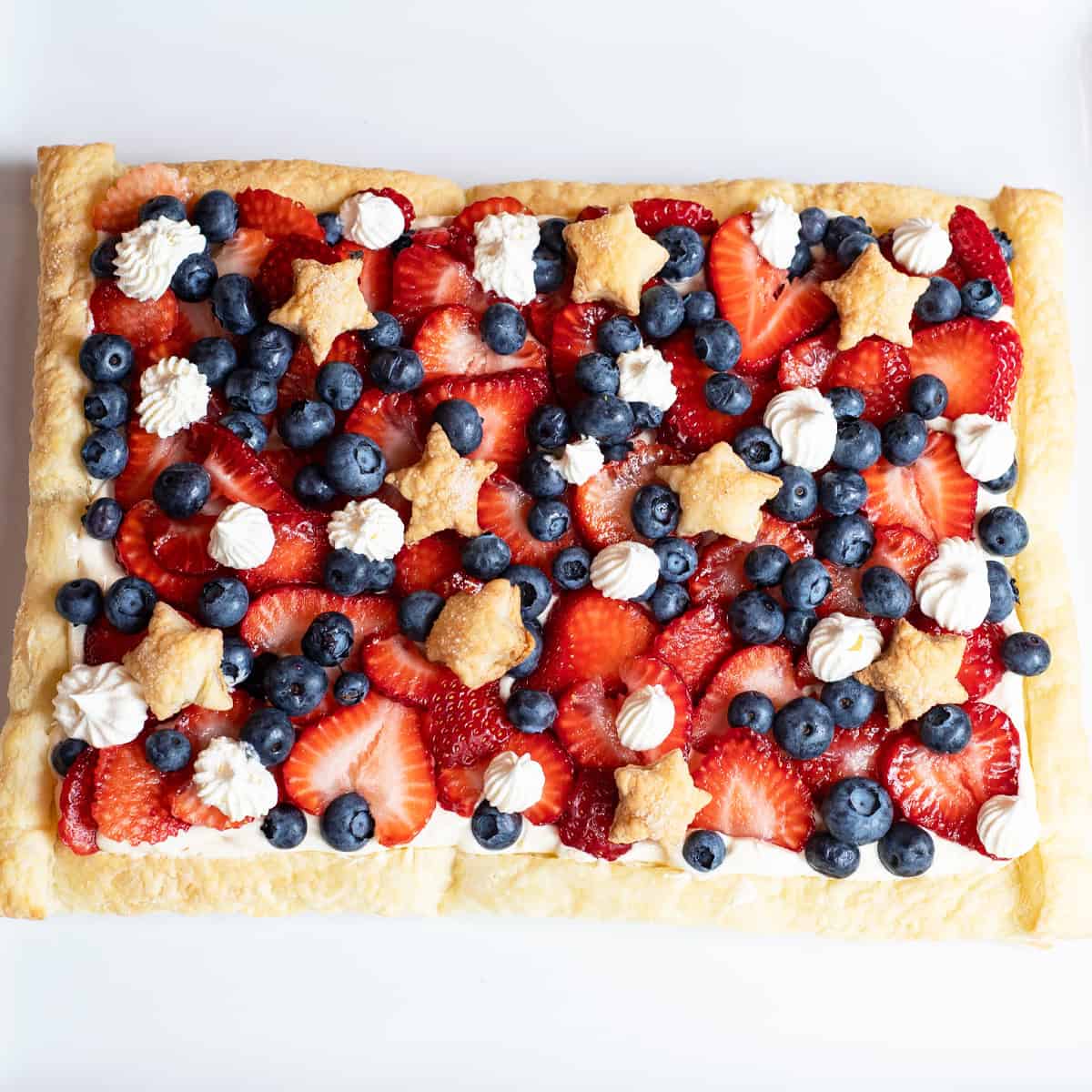 Overhead view of a patriotic Berries and Stars dessert with star-shaped puff pastry and fresh strawberries and blueberries.