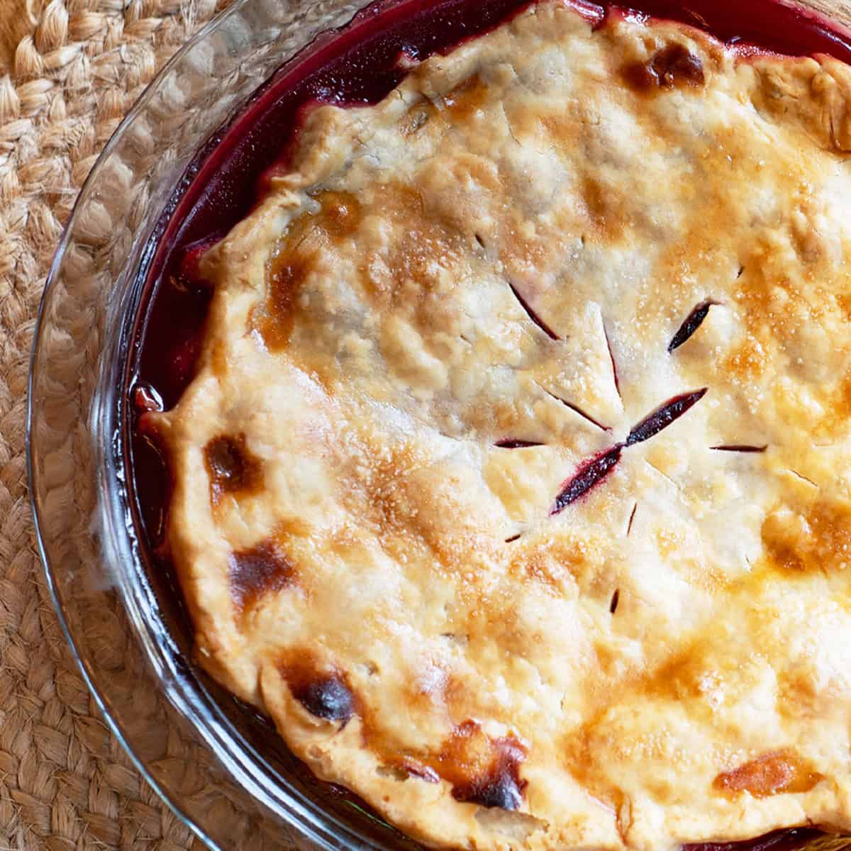 Close-up of half a blackberry pie showing juicy berry filling and flaky crust.