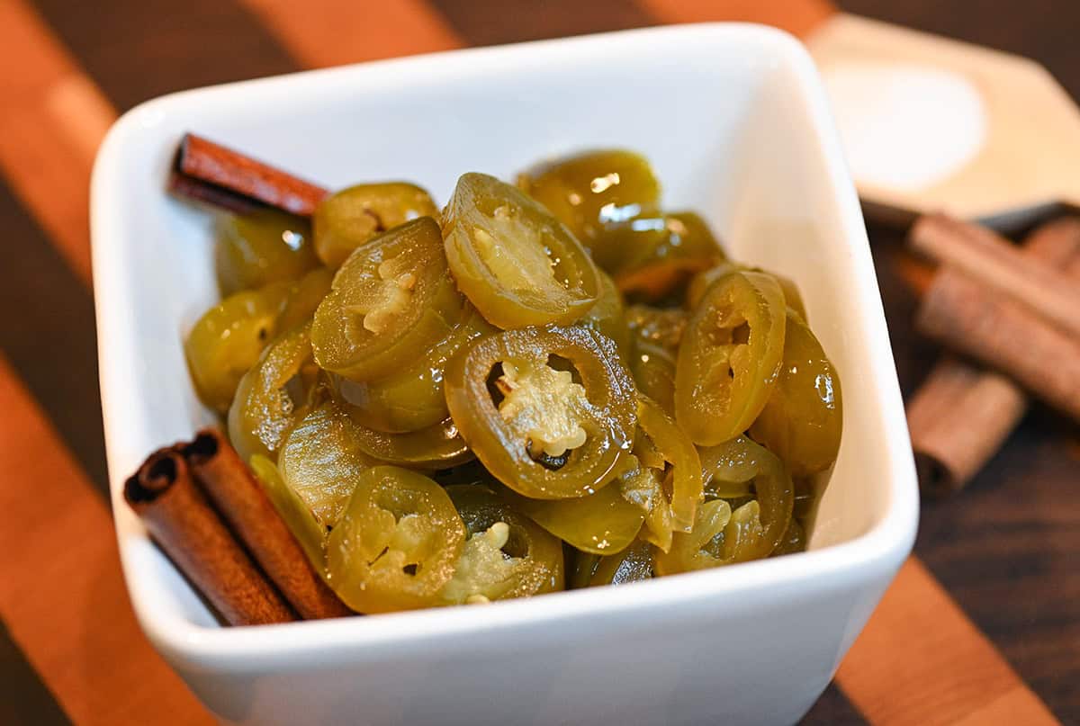 Overhead view of Cowboy Candy in a white bowl filled with sliced jalapeños in a sweet glaze.