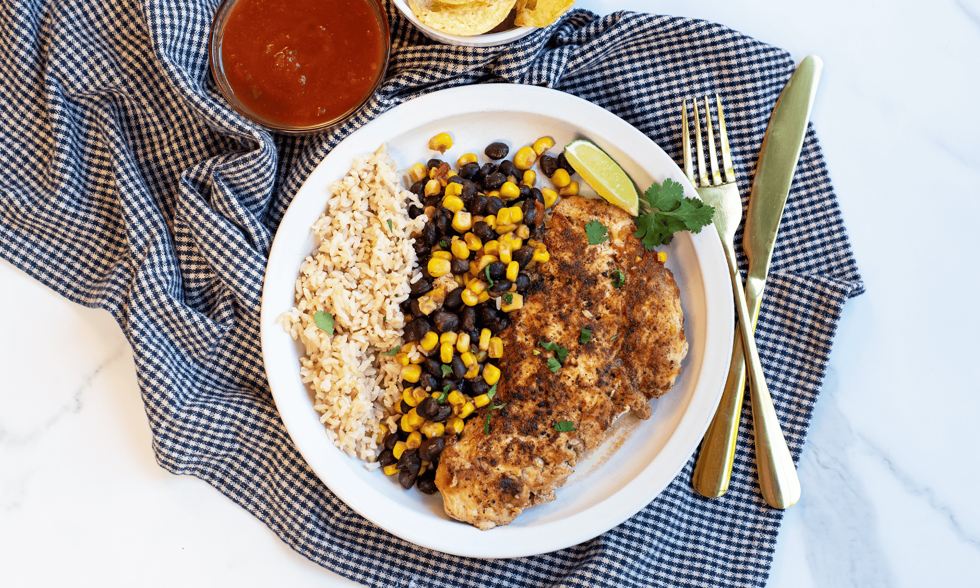 Fiesta Skillet Chicken served over rice with seasoned chicken breasts, black beans, sweet corn, and salsa in a colorful one-pan meal.
