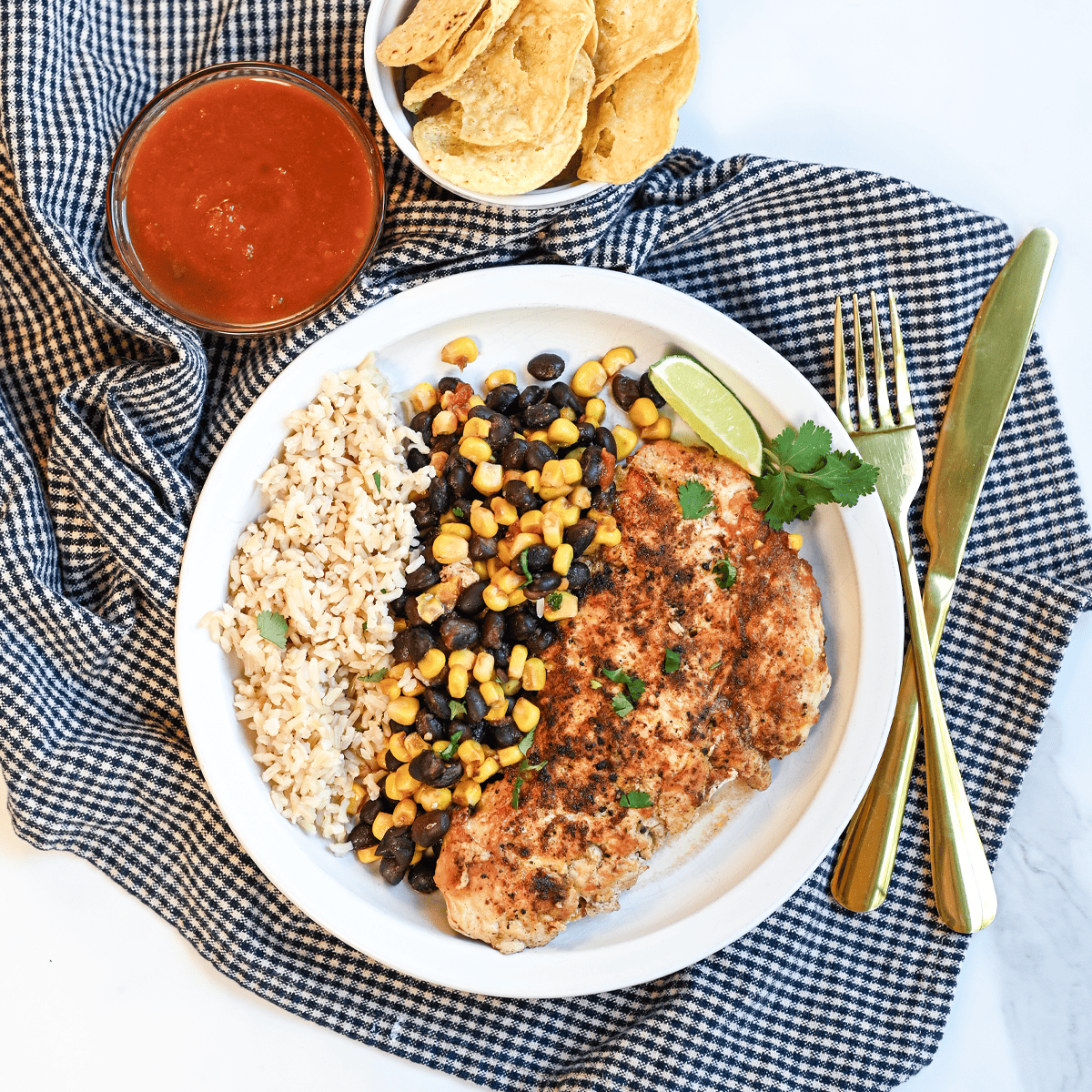 Fiesta Skillet Chicken served over rice with seasoned chicken breasts, black beans, sweet corn, and salsa in a colorful one-pan meal.