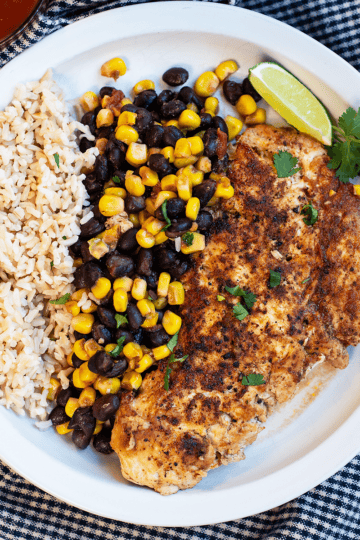 Fiesta Skillet Chicken made with seasoned chicken breasts, black beans, corn, and salsa served over fluffy rice for an easy weeknight dinner.