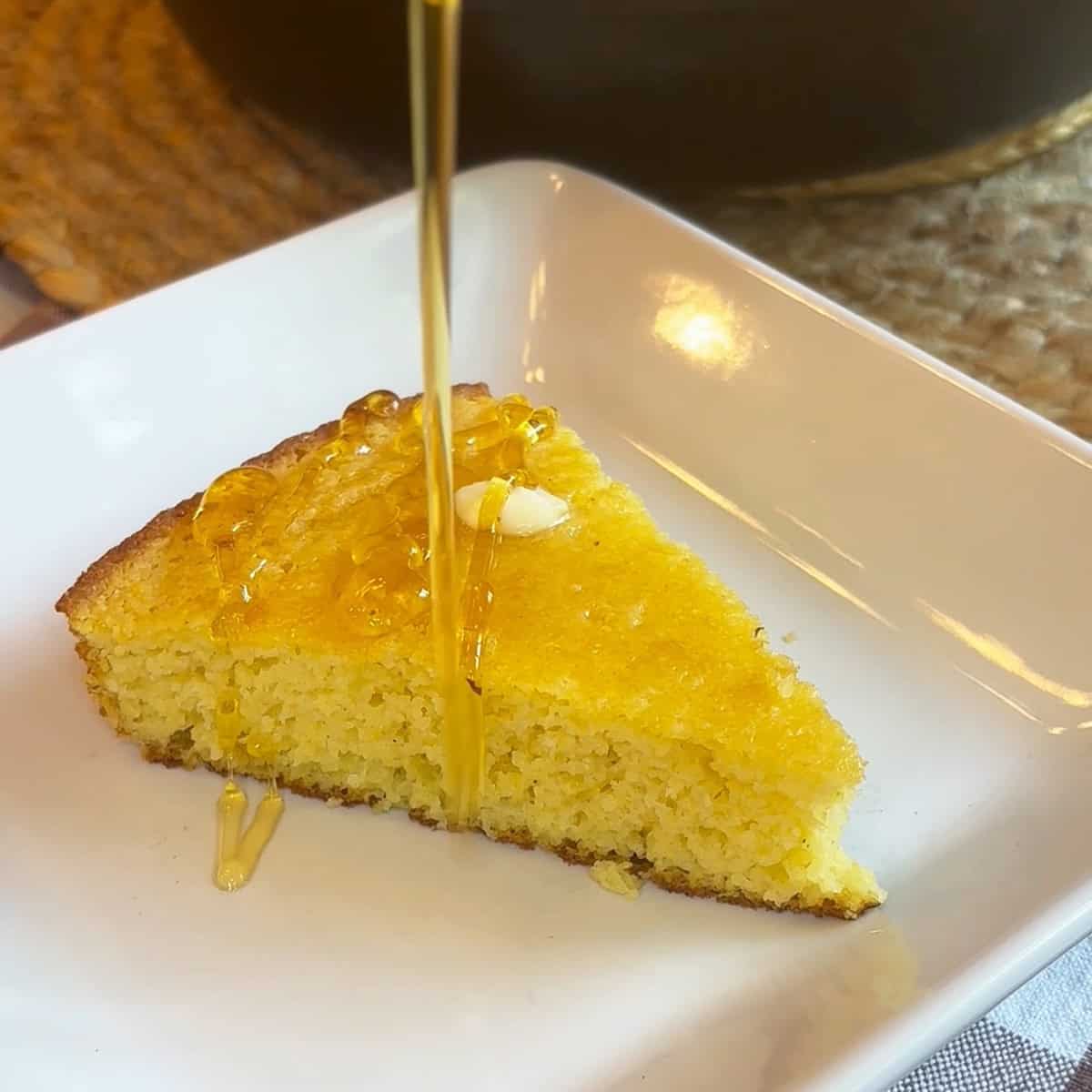Slice of moist cornbread with golden honey drizzling over the top