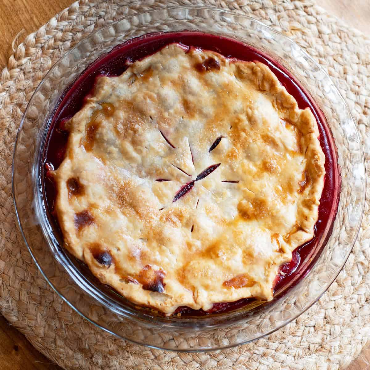 Overhead view of a baked old-fashioned blackberry pie in a glass pie plate.