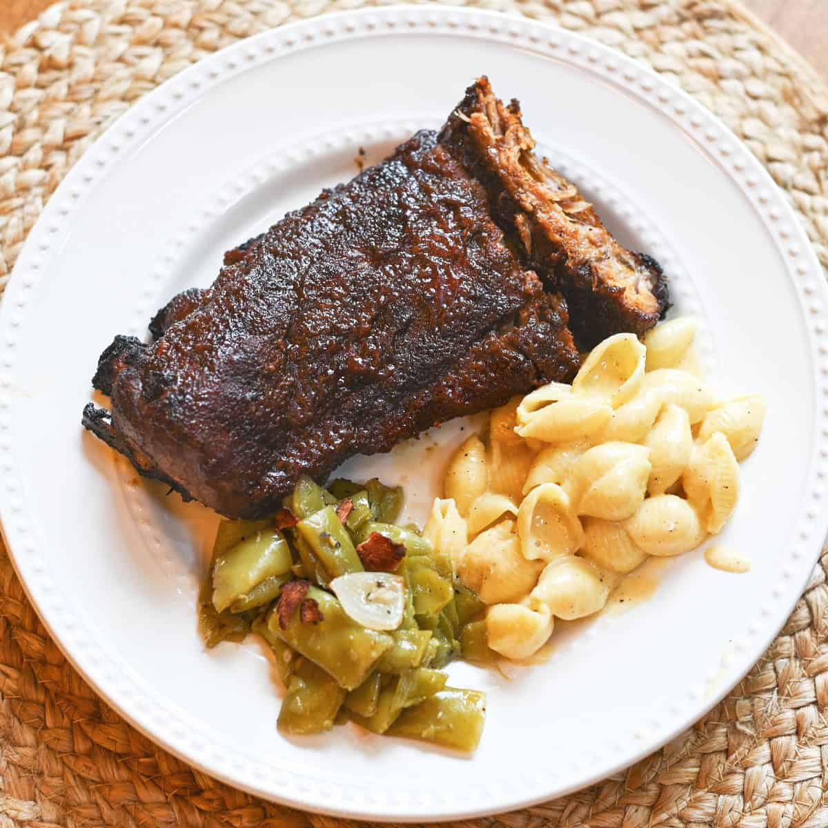 Baby back ribs with classic sides on a white dinner plate.