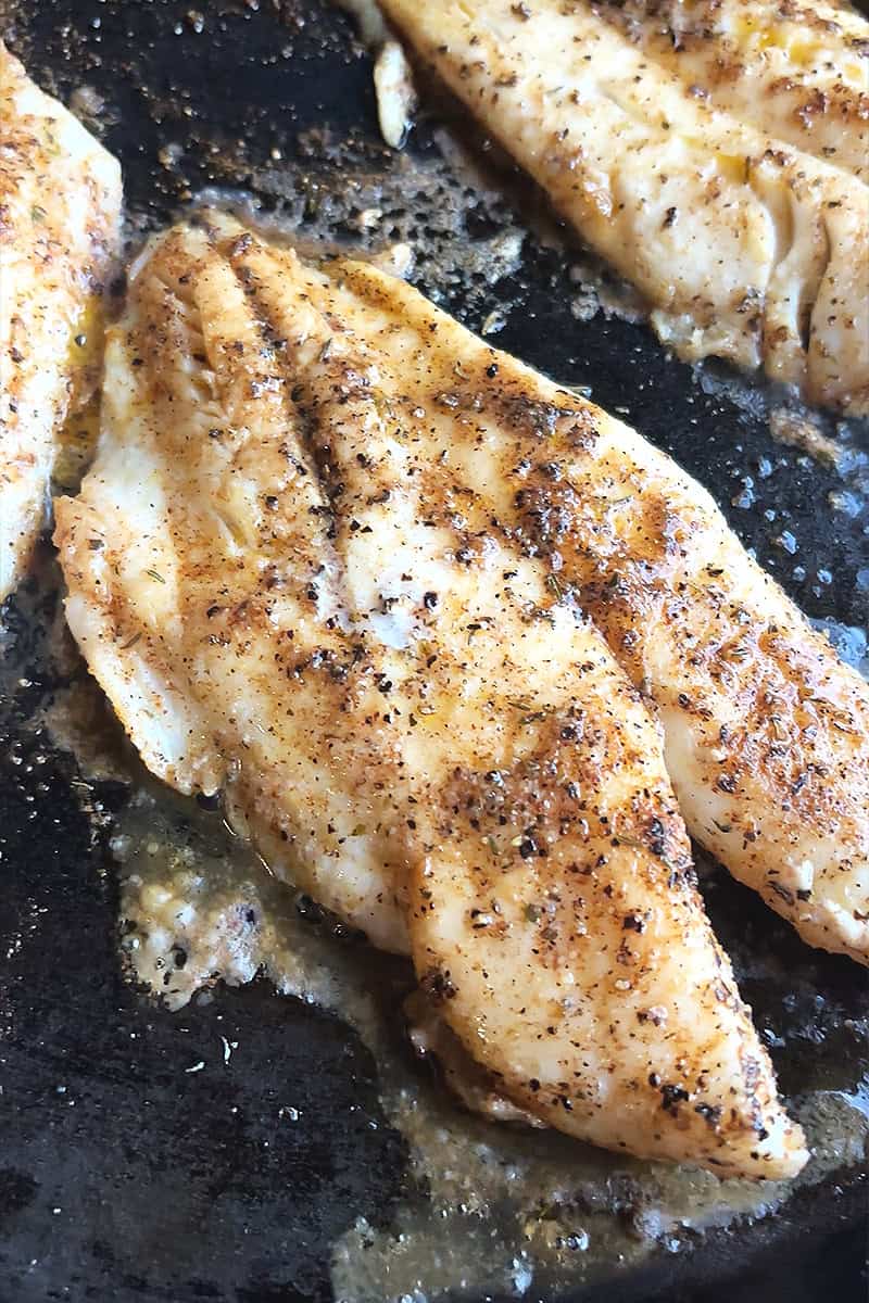 Close-up of a blackened fish fillet with a crispy seasoned crust.