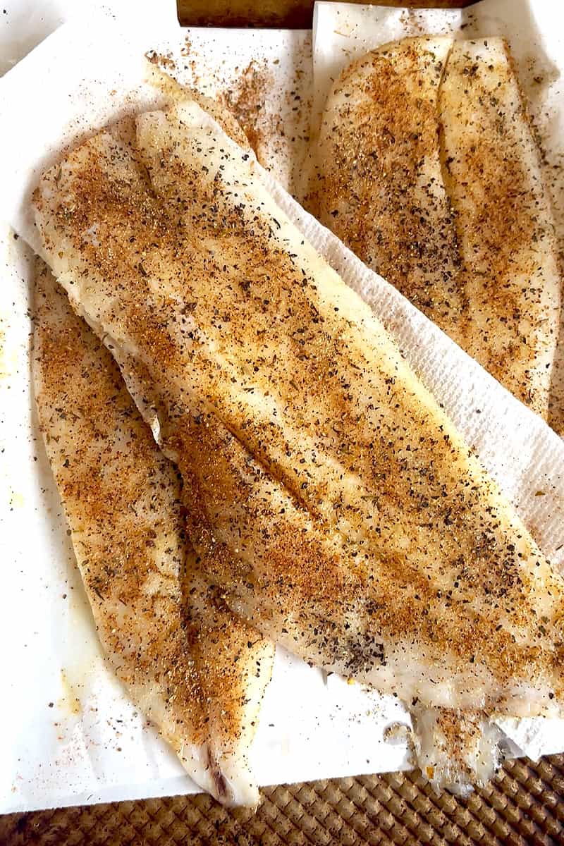 Raw fish fillets coated in blackened seasoning before cooking.