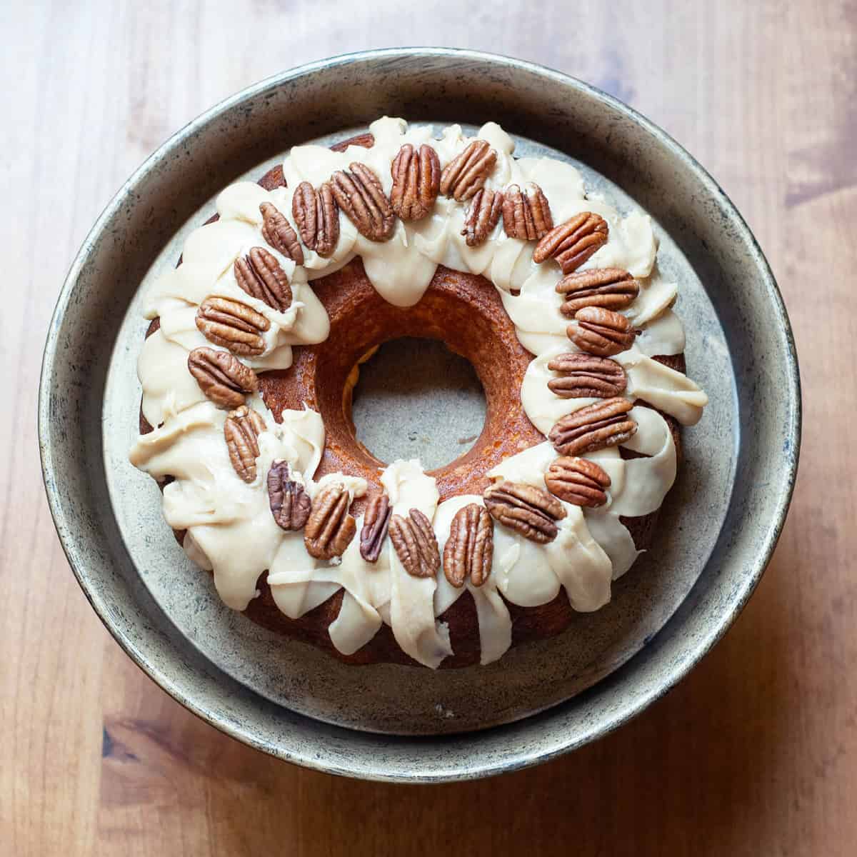 Overhead view of a butter bundt cake topped with praline glaze and whole pecans