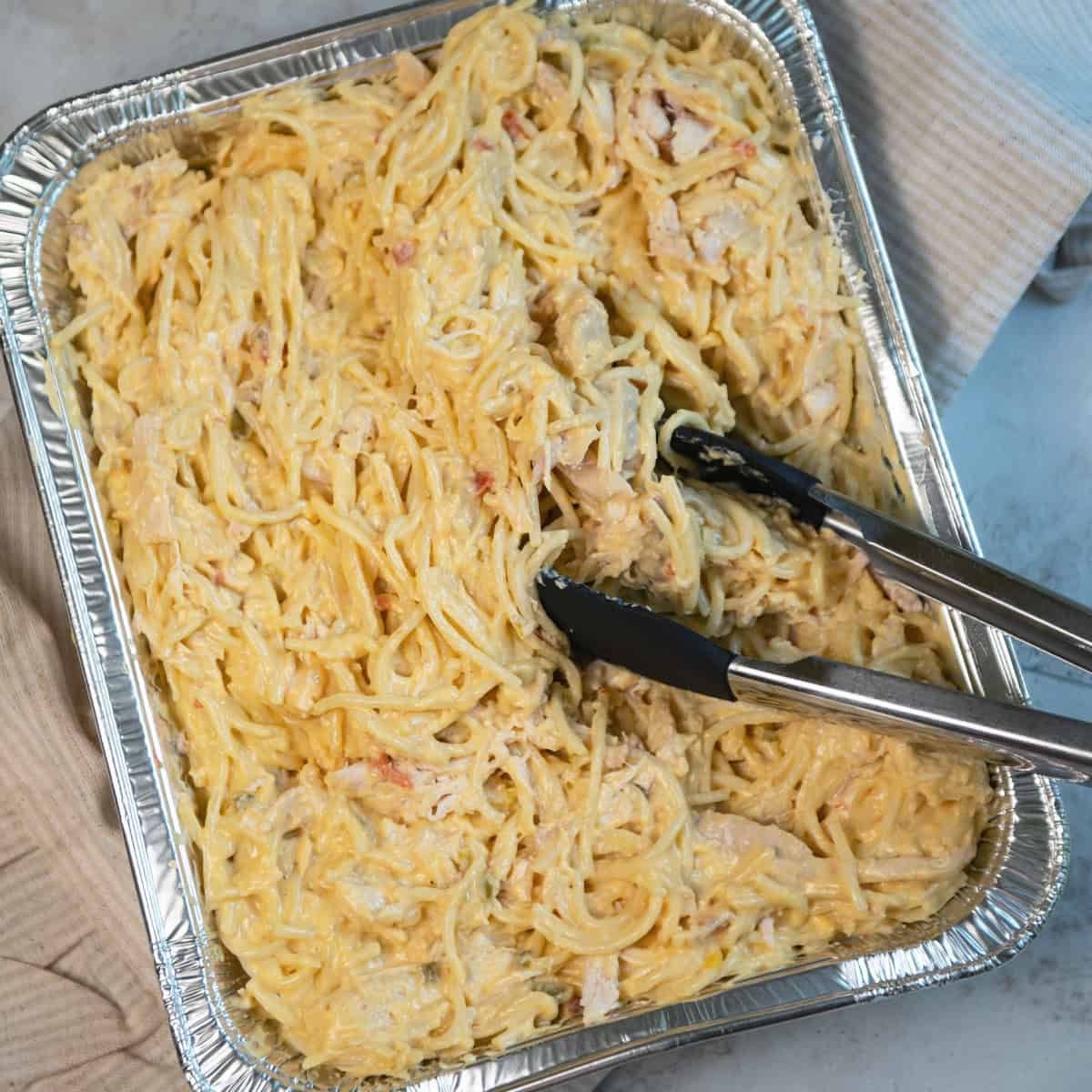 Large foil pan filled with creamy chicken spaghetti, ready to serve a crowd