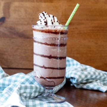 Close-up of a chocolate frappe with rich chocolate swirls and a paper straw.