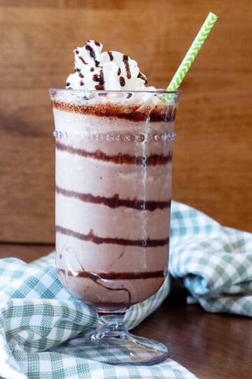 Close-up of a chocolate frappe with rich chocolate swirls and a paper straw.