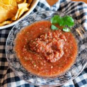 Overhead shot of restaurant-style salsa in a bowl surrounded by tortilla chips.
