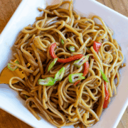 Overhead view of ginger soy noodles with colorful vegetables on a white plate.