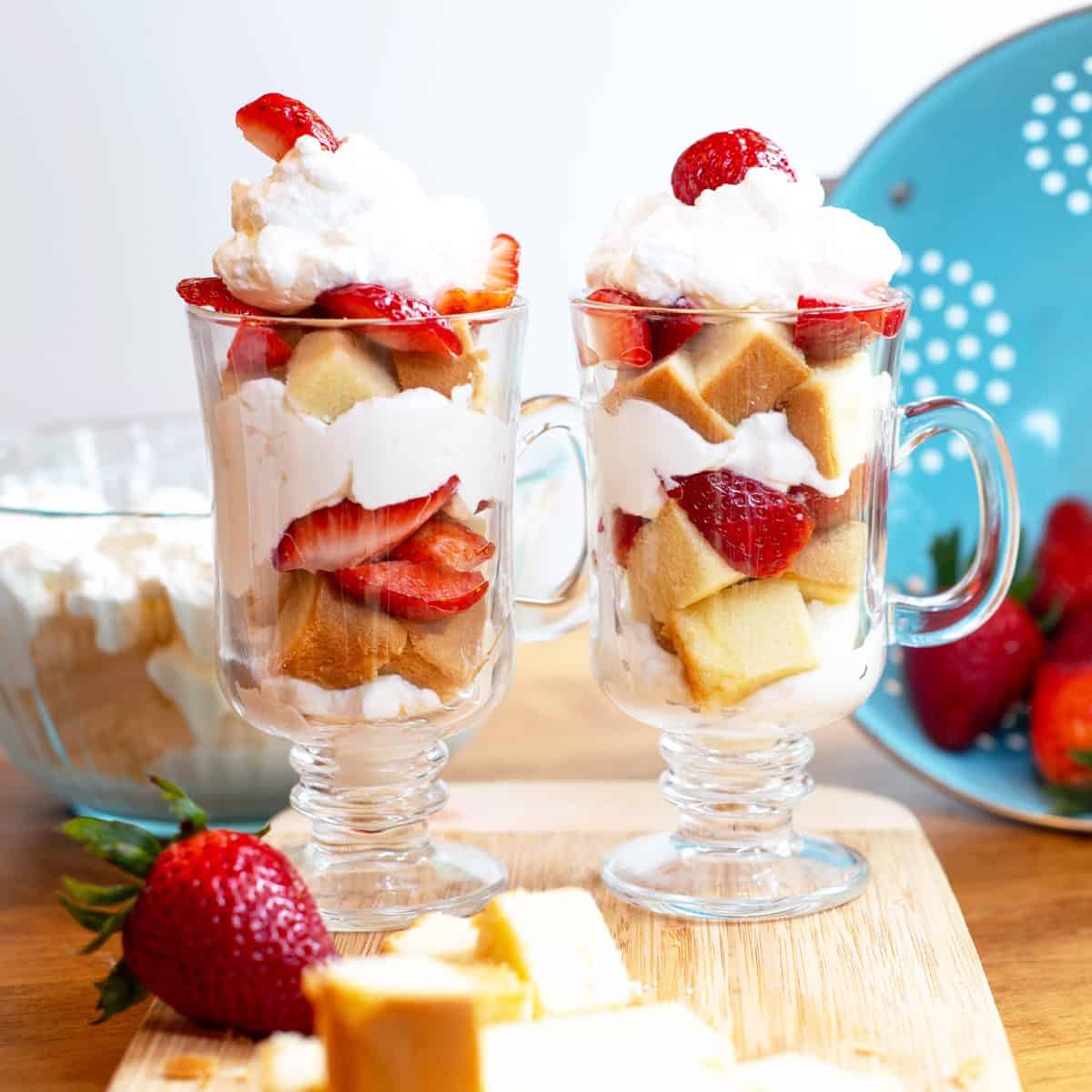 Two individual strawberry shortcake trifles in clear glasses on a serving tray, ready to enjoy.