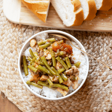 verhead image of a bowl of Creole chicken stew served with crusty whole wheat bread on the side.