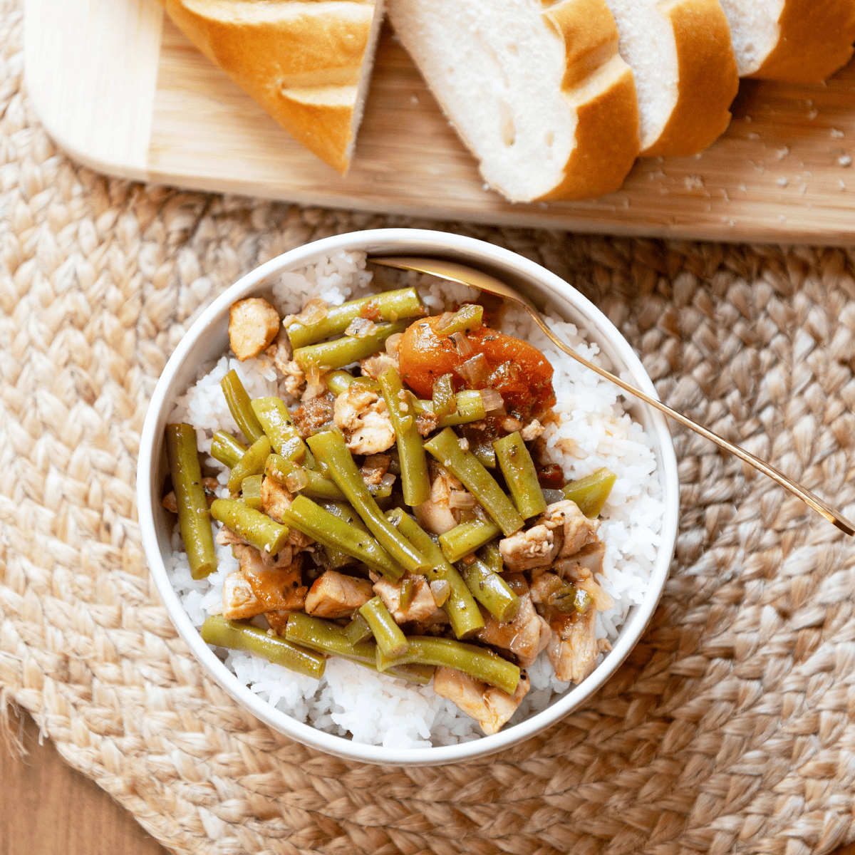 verhead image of a bowl of Creole chicken stew served with crusty whole wheat bread on the side.