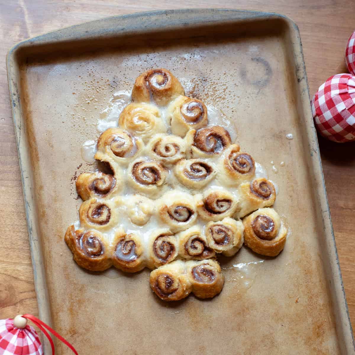 Christmas tree-shaped mini cinnamon rolls surrounded by festive ornaments.