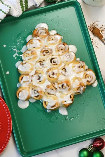 Mini Cinnamon Rolls tree with glaze on a green baking sheet