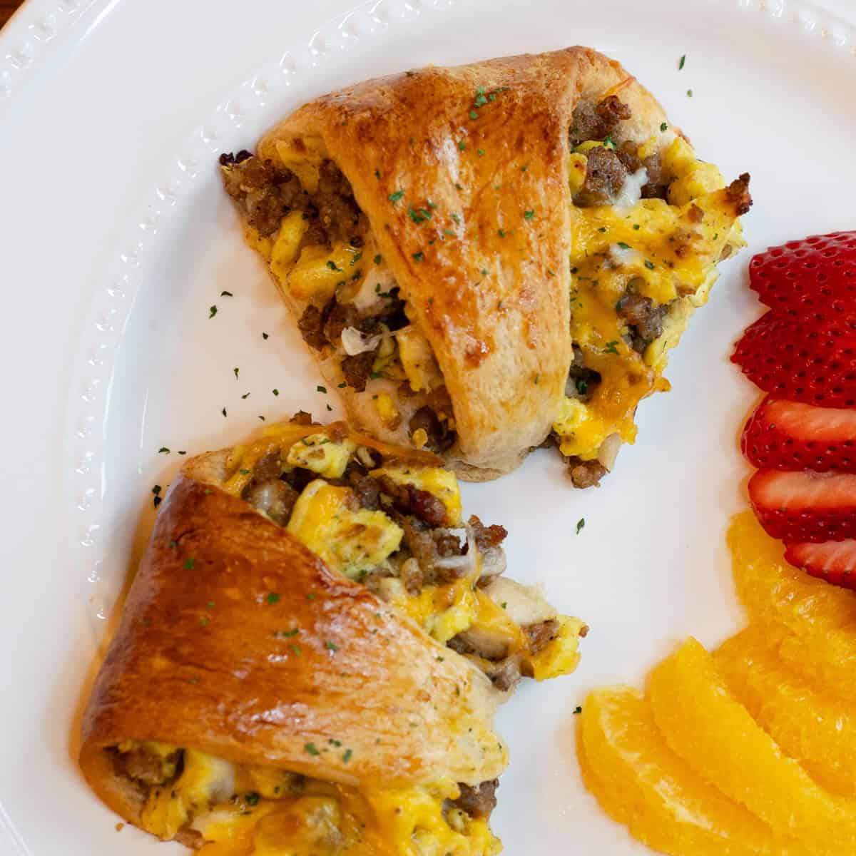 Sliced crescent ring served on a plate with fresh fruit on the side.