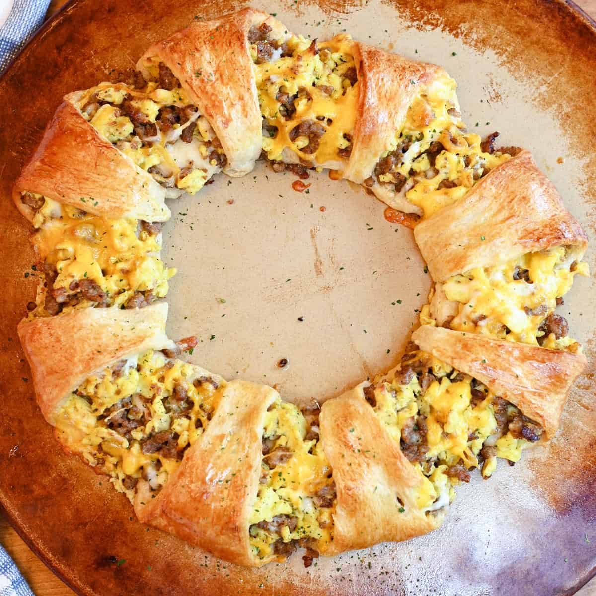 Golden baked egg and sausage crescent ring arranged in a circle on a pizza stone.