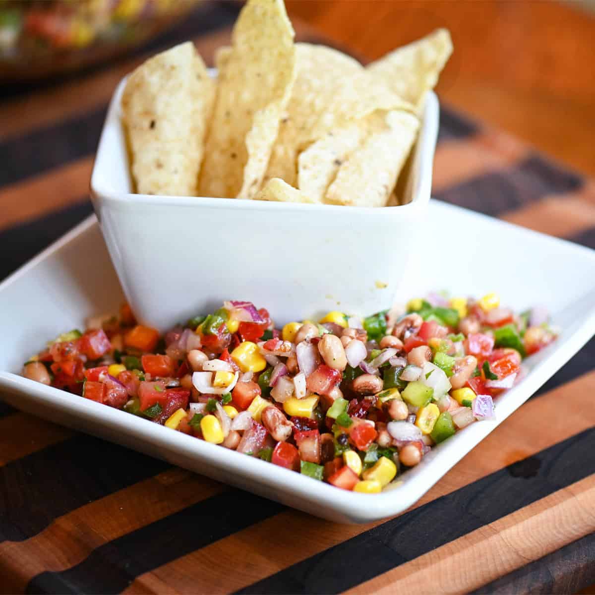 Side angle of Texas Caviar on a plate with tortilla chips in the background.