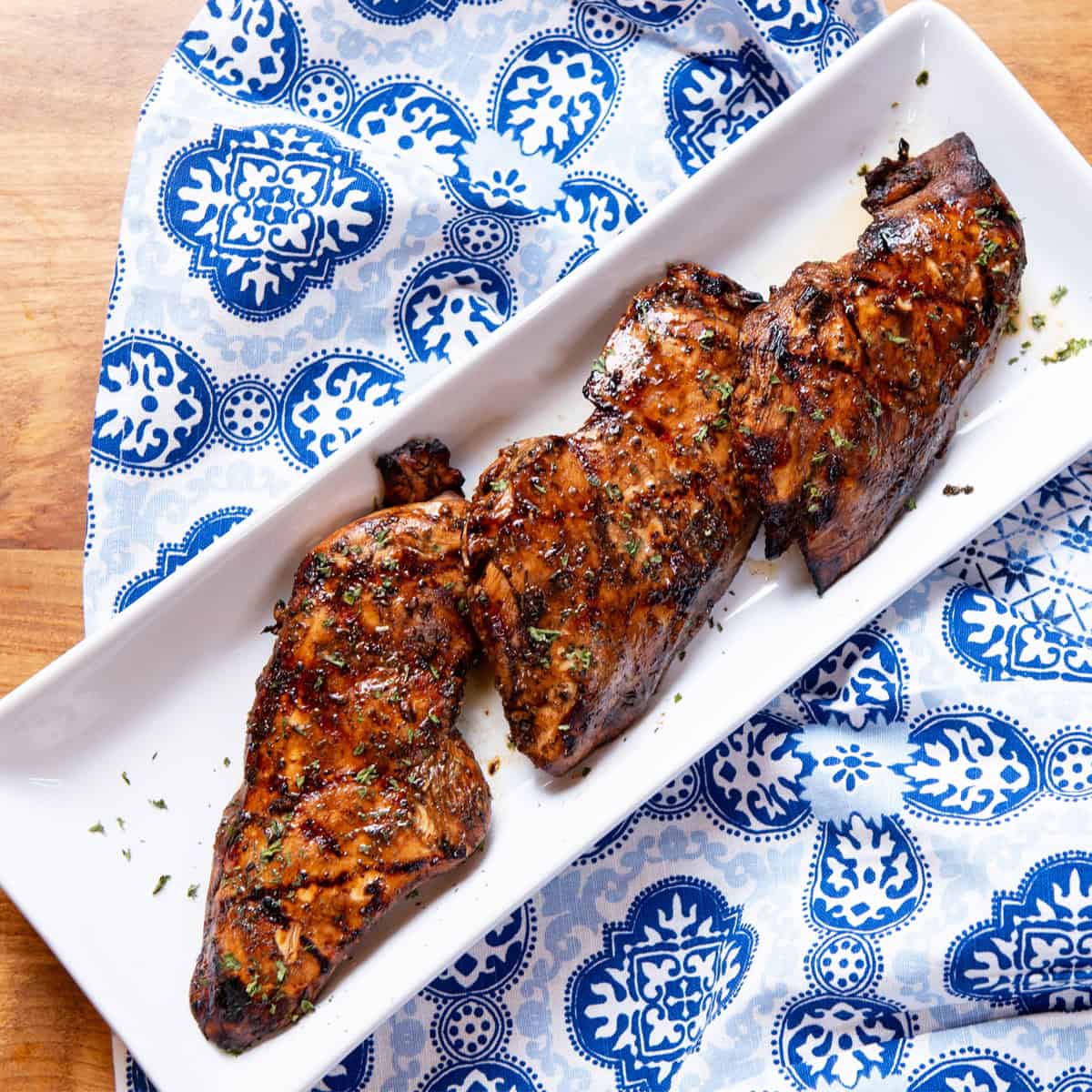 Grilled chicken breasts with char marks, garnished with herbs ready to serve on white platter
