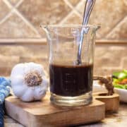 Glass jar of homemade balsamic vinaigrette surrounded by fresh salad ingredients