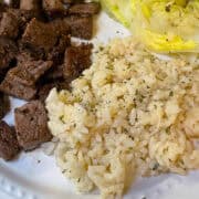 Creamy Parmesan rice served on a plate with juicy steak bites.