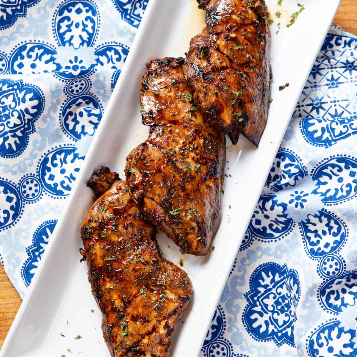 Grilled chicken breasts with char marks, garnished with herbs ready to serve on white platter