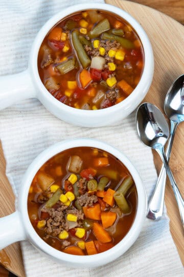 Two white bowls filled with old-fashioned beef vegetable soup on a table.