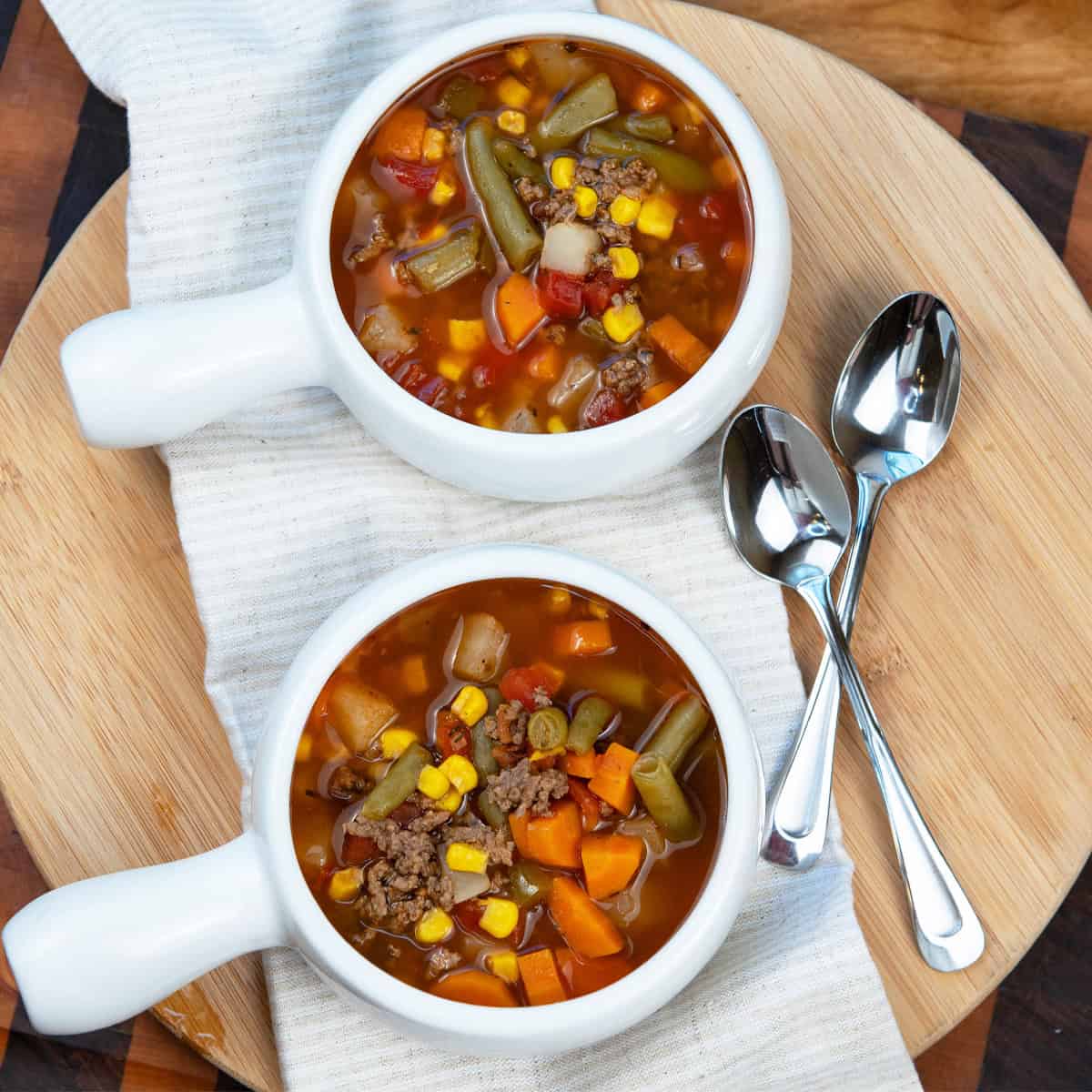 Two white bowls filled with old-fashioned beef vegetable soup on a table.