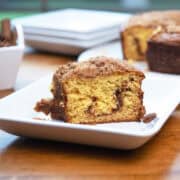 Slice of cinnamon crumb cake with a rich cinnamon swirl and crumb topping on a white plate.