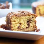 Slice of cinnamon crumb cake with a rich cinnamon swirl and crumb topping on a white plate.