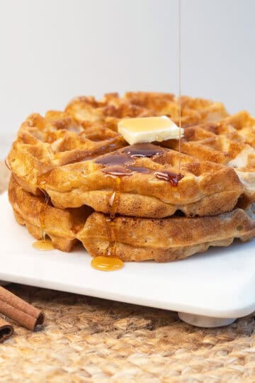 Overhead view of cinnamon waffles topped with butter and syrup.