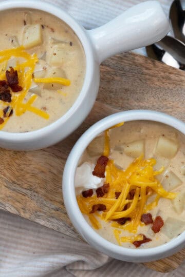 Overhead close-up of potato soup with garnishes in a white bowl.