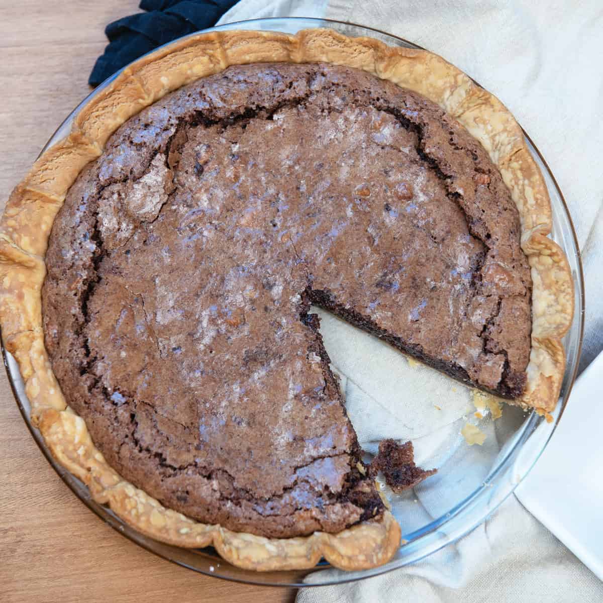whole fudge pie with pecans missing just one gooey slice