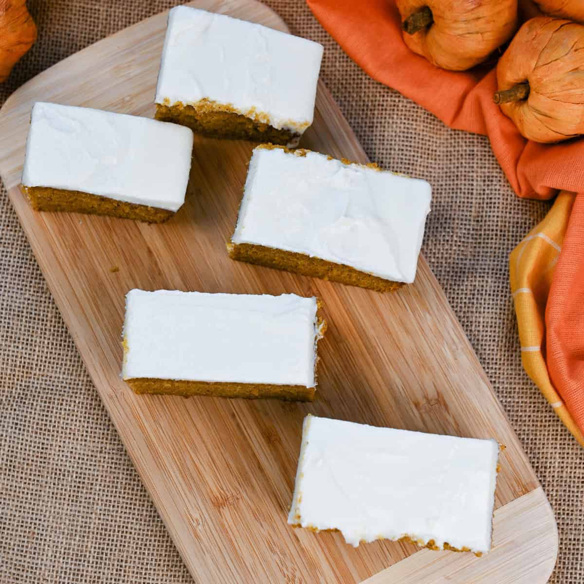 Overhead view of pumpkin bars with cream cheese frosting on serving board