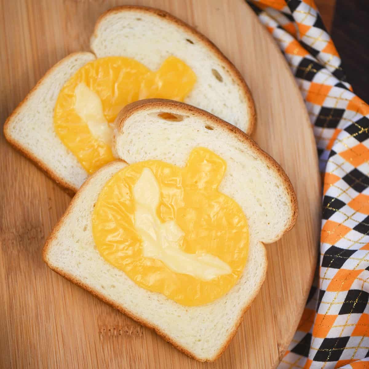 Halloween-themed cheese toast in the shapes of pumpkins and bats on a plate.