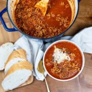Overhead view of a pot of lasagna soup with a full bowl beside it, ready to serve