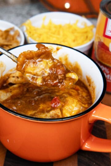 Close-up of a spoonful of pumpkin chili with beans, meat, and tomato