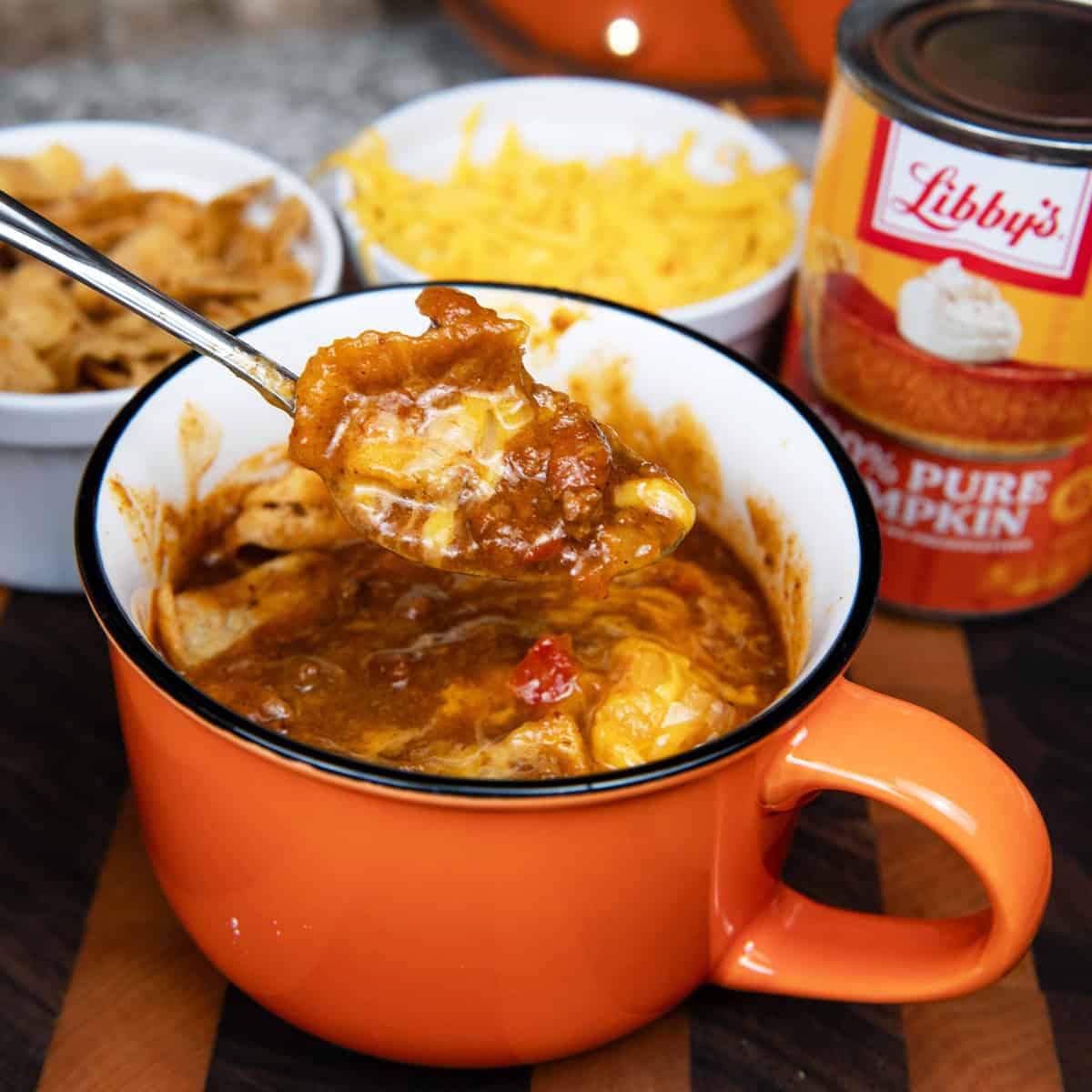 Close-up of a spoonful of pumpkin chili with beans, meat, and tomato