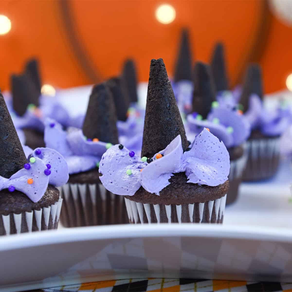 Witch Hat Mini Cupcakes arranged on a white serving platter with purple frosting and waffle cone hats.