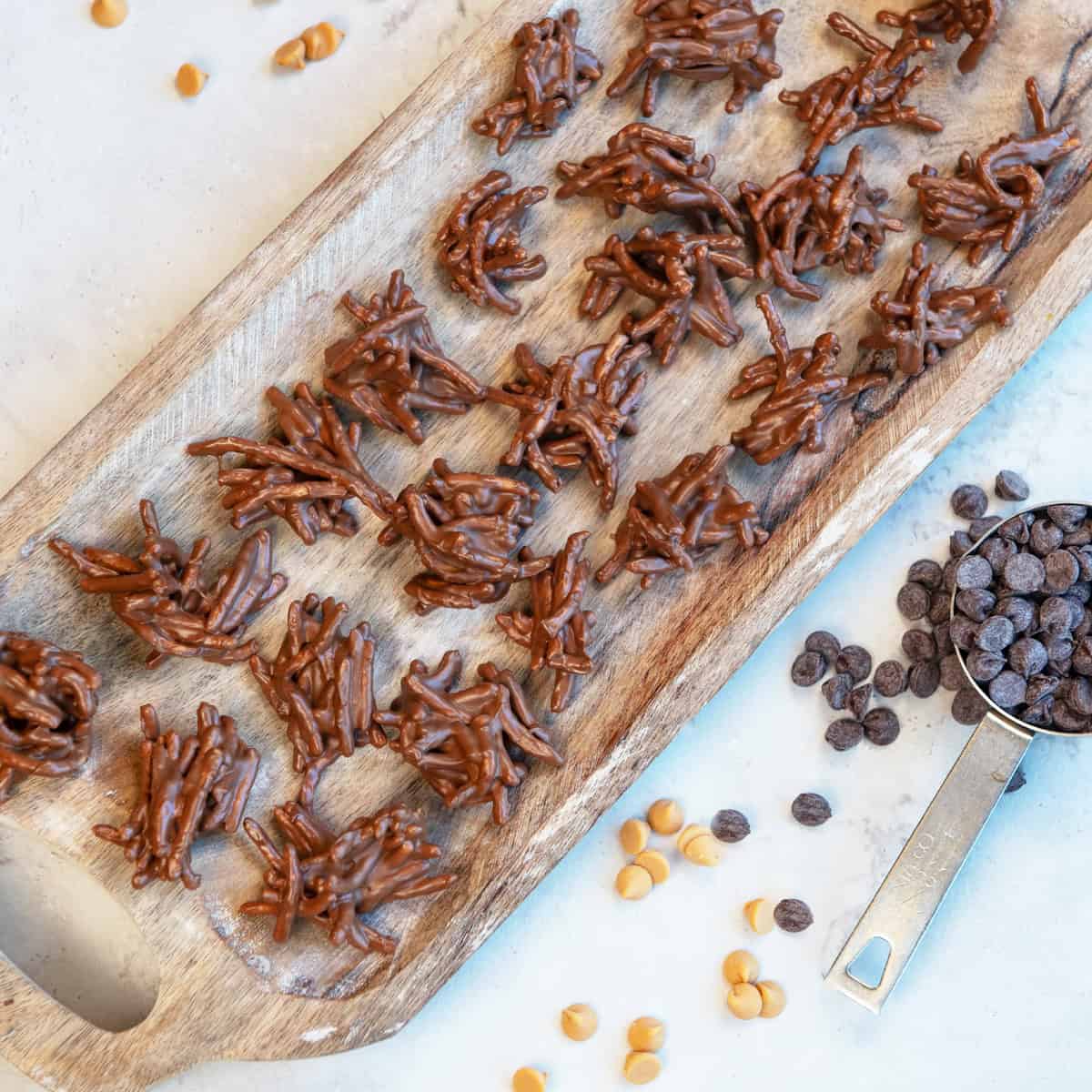 No-bake chocolate haystacks made with chow mein noodles, stacked in clusters on parchment paper.