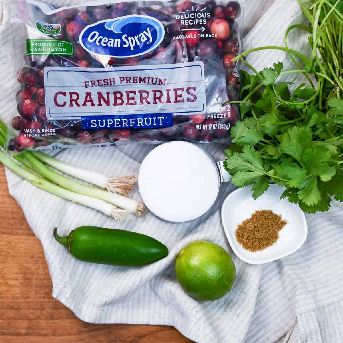 Overhead shot of fresh ingredients for cranberry salsa including cranberries, jalapeños, onion, lime, and cilantro