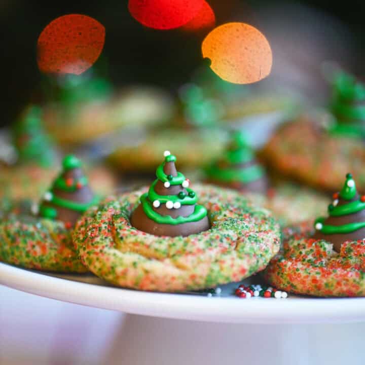 Side view of peanut butter kiss cookies decorated like Christmas trees on a white platter