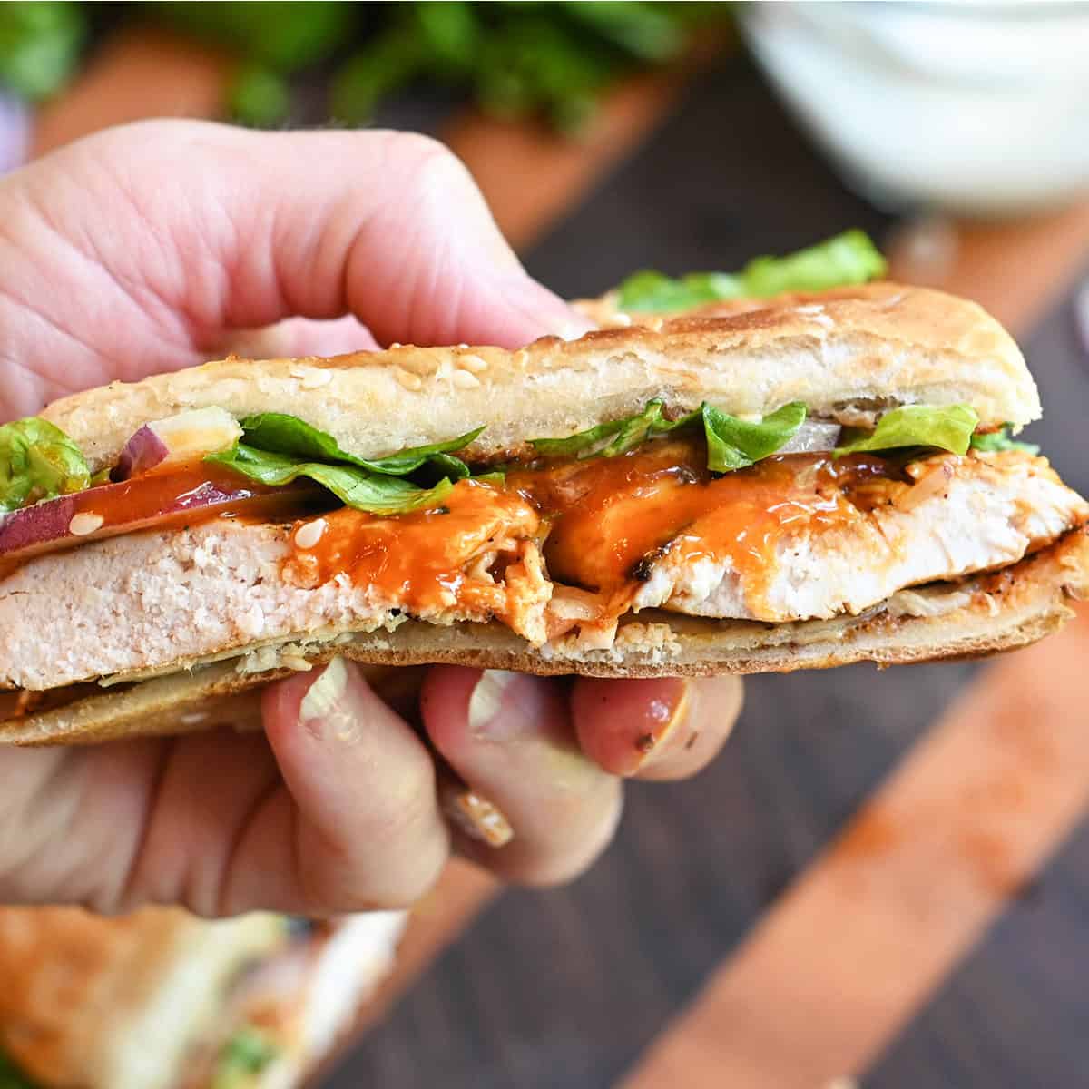 Grilled buffalo chicken sandwich topped with ranch dressing and lettuce on a toasted bun