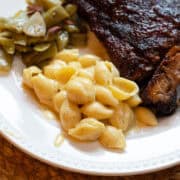 A serving of creamy shells and cheese with tender ribs on a white plate.