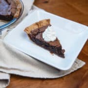 Slice of fudge pie with pecans, served on a white plate