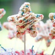 Star-shaped patriotic Rice Krispie treats drizzled with white chocolate and decorated with red, white, and blue cereal.